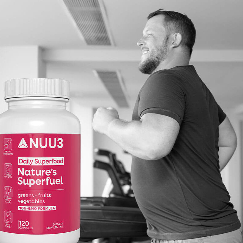 Person in a gym holding a supplement bottle labeled 'NUU3' with a pink label.