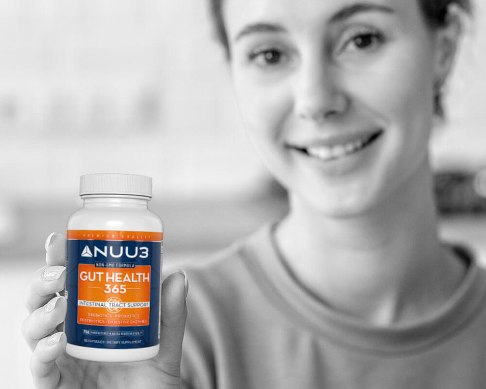 Person holding a bottle of NUU3 Gut Health 365 supplement with a blurred background