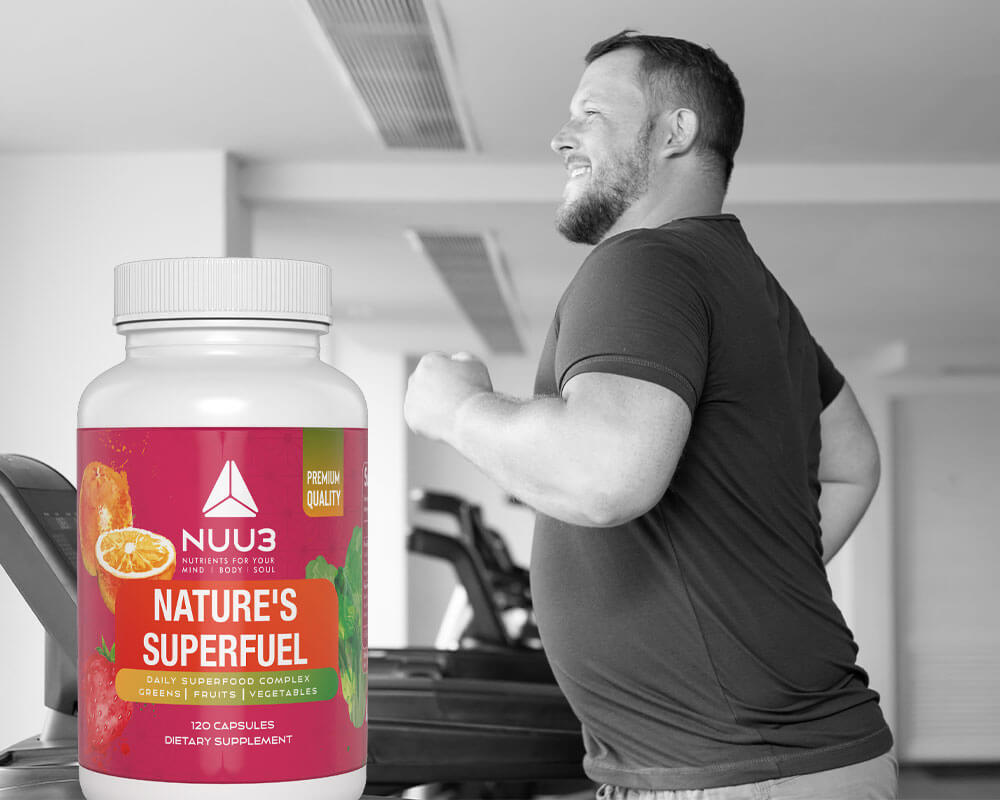 Person in a gym holding a supplement bottle labeled 'NUU3' with a pink label.
