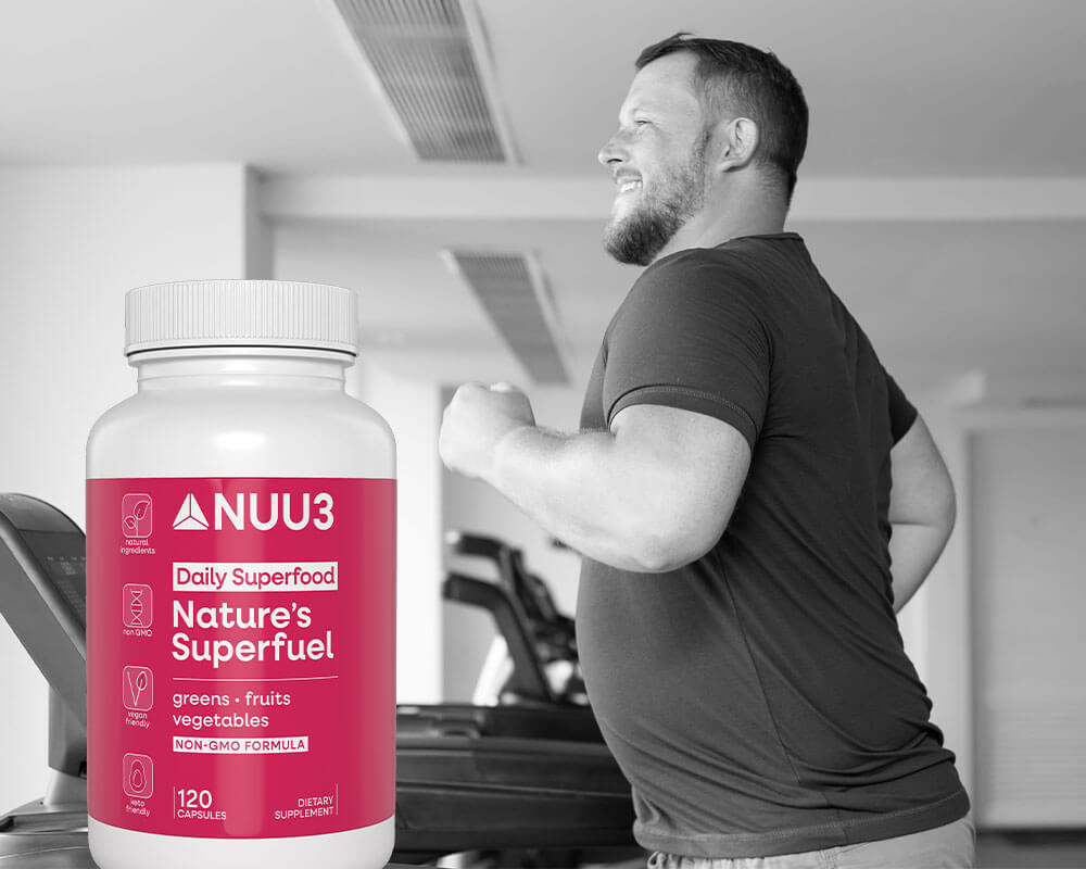 Person in a gym holding a supplement bottle labeled 'NUU3' with a pink label.